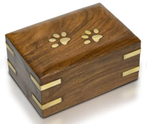 A wooden pet urn with engraved paw prints on the lid.