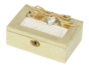 A rustic wooden musical keepsake box with a heart ornament and a prayer card attached to the lid